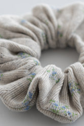 Close-up of pebble green ribbed scrunchie with pastel blue and green floral pattern – Avauma